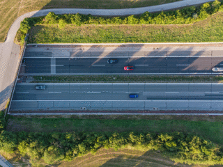 Luftaufnahme einer mehrspurigen Bundesstraße mit Fahrzeugverkehr, eingebettet in eine grüne Landschaft